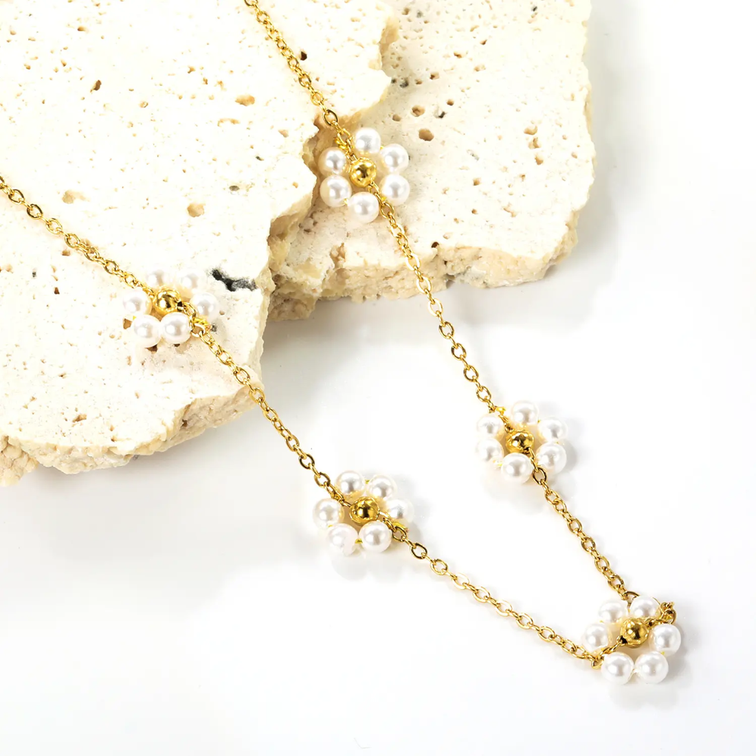 Gold necklace with floral beads on a soft white fabric background